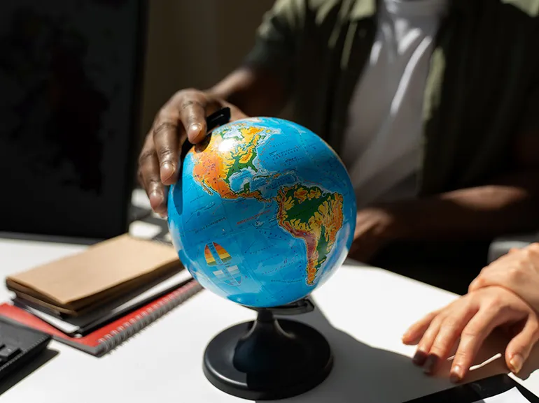 An image of a hand touching a globe An image of a hand touching a globe